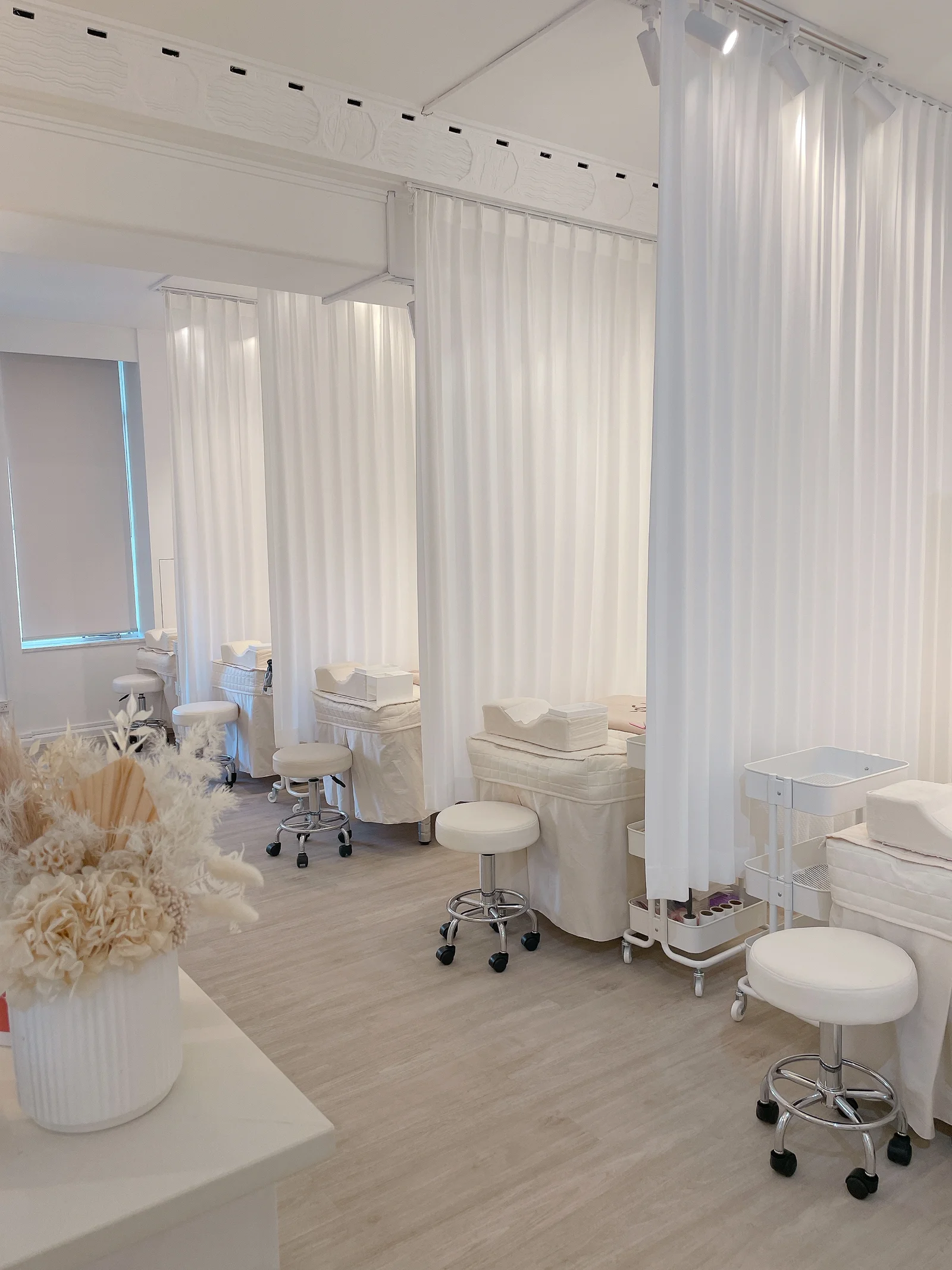 éclaire treatment room — white curtained stations and cream beds